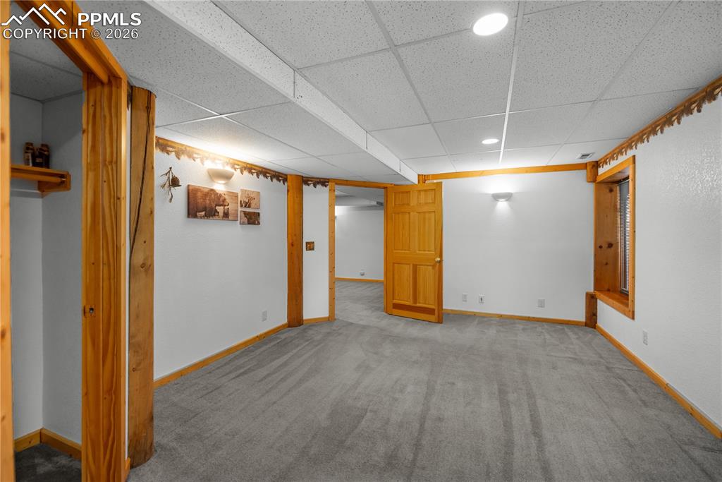 Image 33 of 45: Finished basement with a paneled ceiling, carpet floors, and recessed light