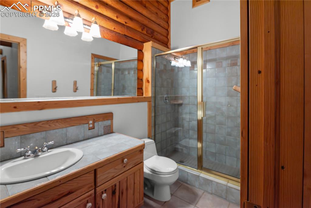 Image 35 of 45: Full bathroom featuring vanity, a stall shower, tile patterned flooring, an