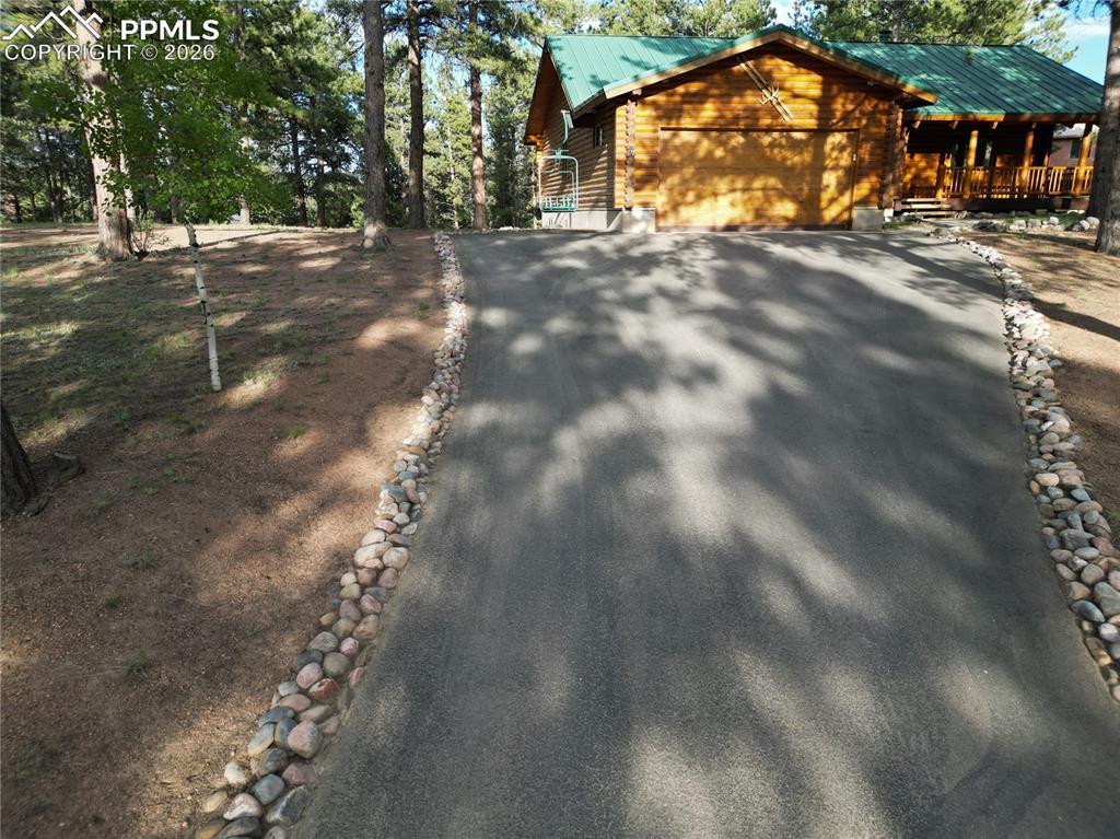 Image 45 of 45: View of front of house with driveway, a garage, a metal roof, and a porch