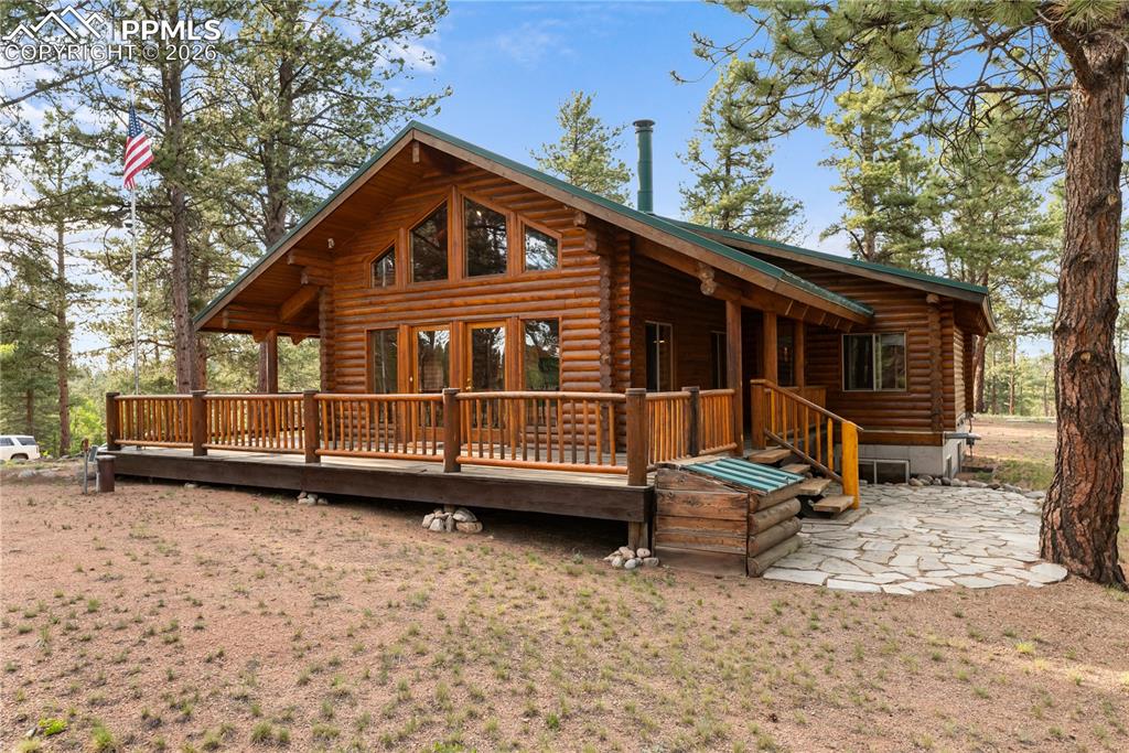 Image 6 of 45: View of front facade featuring log exterior, a wooden deck, and french door
