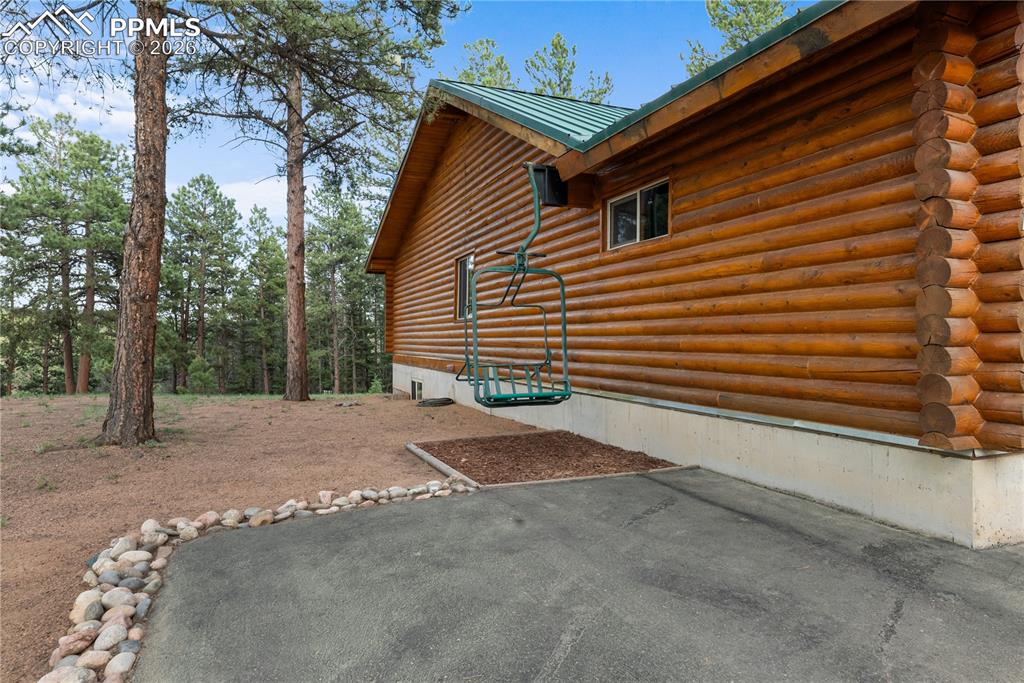 Image 7 of 45: View of property exterior with log exterior, a metal roof, and a patio