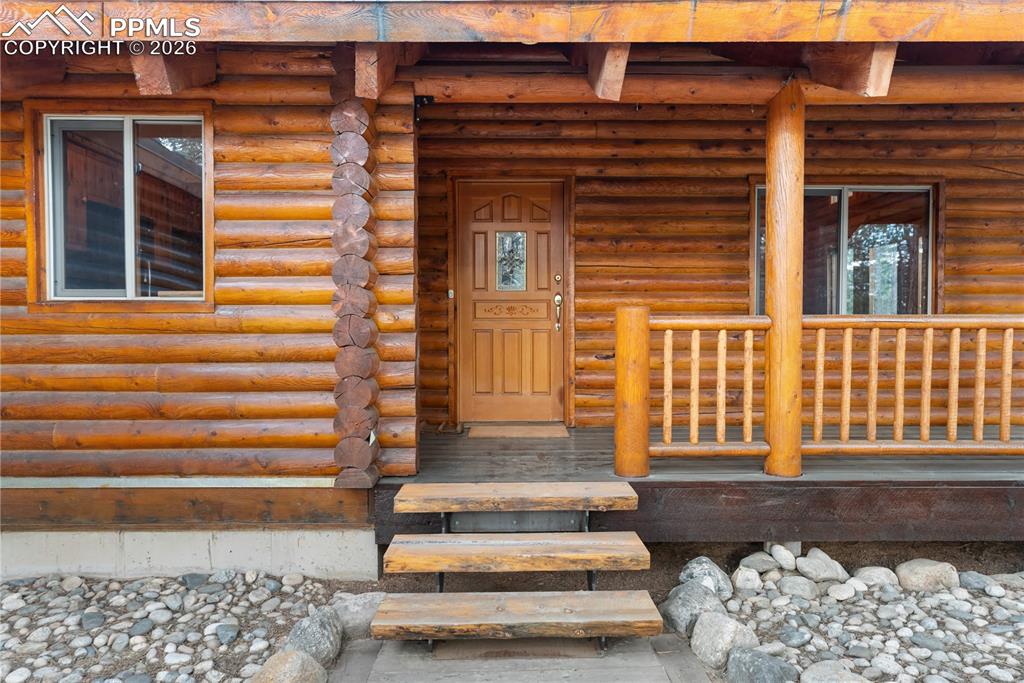 Image 8 of 45: Entrance to property featuring log exterior and a porch