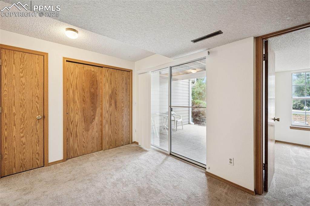 Image 20 of 48: Unfurnished bedroom featuring a textured ceiling, carpet, access to exterio