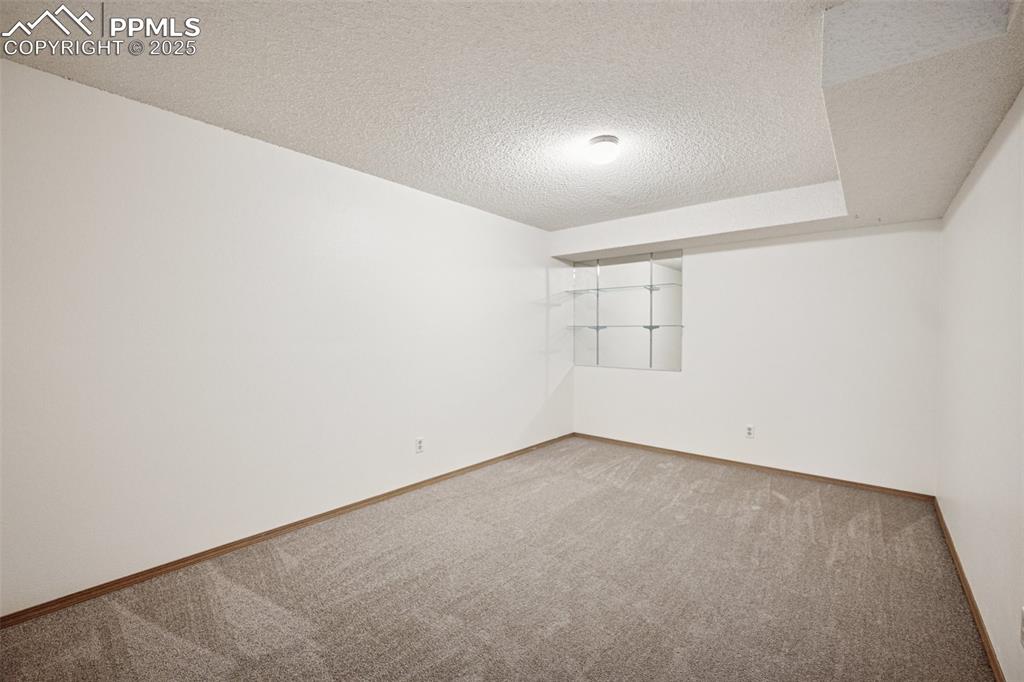 Image 22 of 48: Carpeted room with a textured ceiling and baseboards