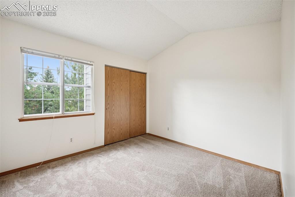 Image 37 of 48: Unfurnished bedroom with carpet flooring, lofted ceiling, a textured ceilin