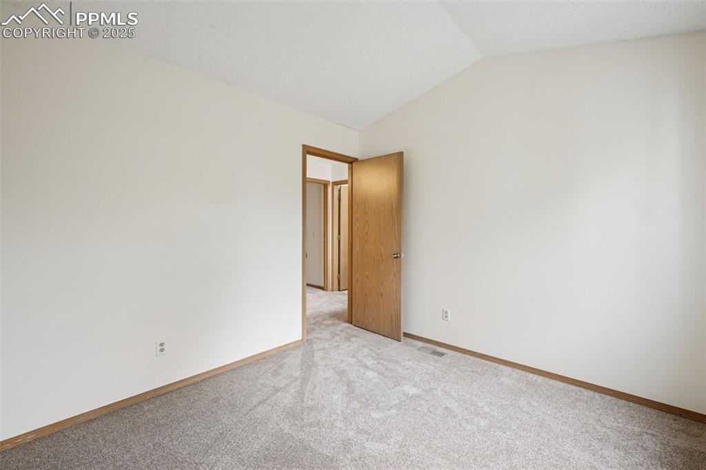 Image 38 of 48: Empty room with lofted ceiling and carpet