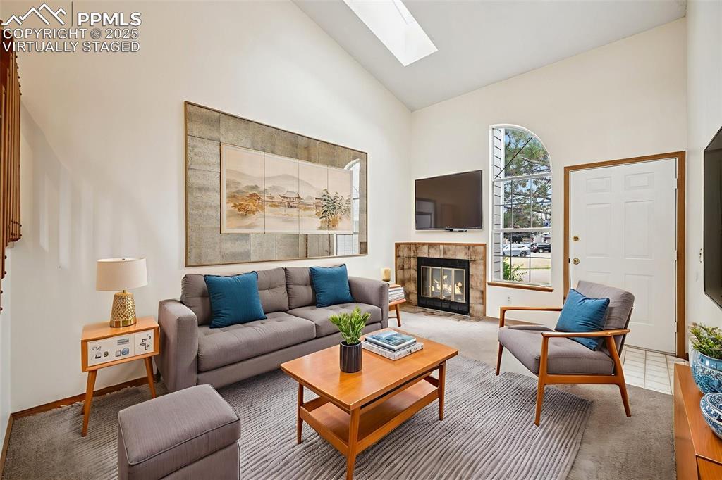 Image 4 of 48: virtually staged - Carpeted living area with high vaulted ceiling, a skylig