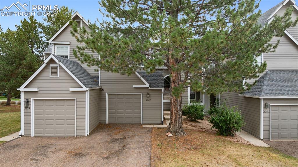 Image 43 of 48: View of front of property featuring a shingled roof, a garage, and asphalt 