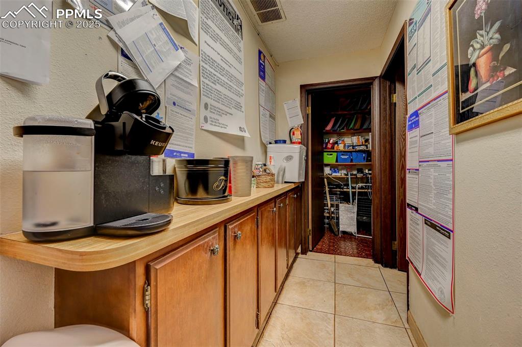 Image 17 of 45: Kitchen featuring light countertops, brown cabinets, a textured ceiling, an