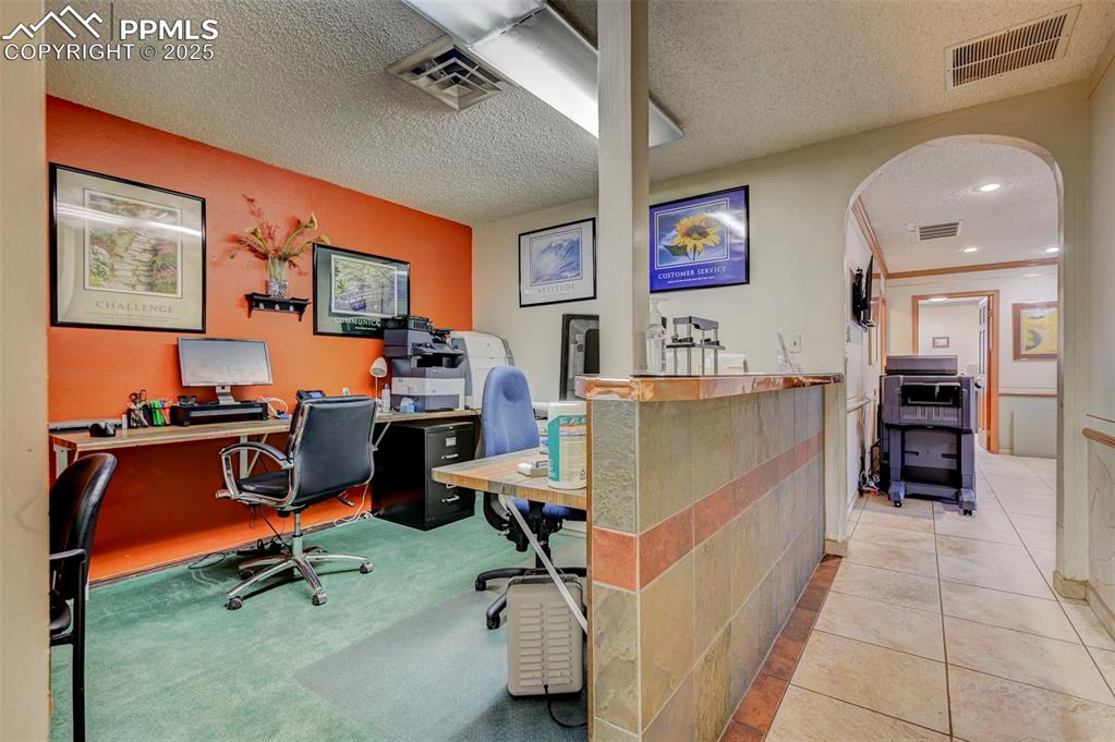Image 25 of 45: Tiled office space with arched walkways and a textured ceiling