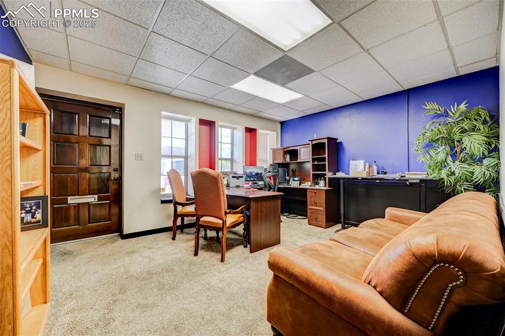 Image 34 of 45: Office area featuring light carpet, a drop ceiling, and baseboards