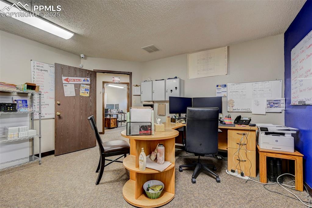 Image 41 of 45: Office area with light colored carpet and a textured ceiling