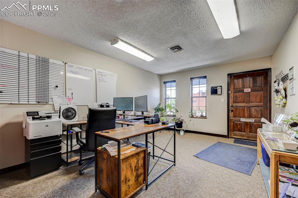 Image 42 of 45: Office space with a textured ceiling, carpet flooring, and baseboards