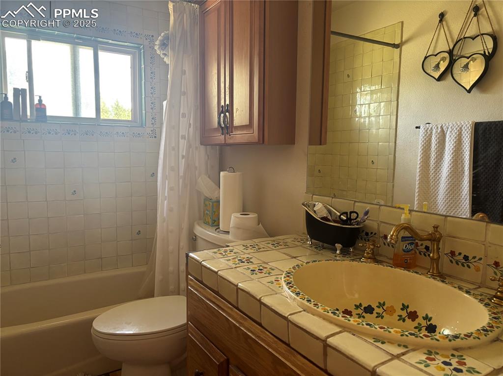 Image 11 of 25: Bathroom with shower / bath combo with shower curtain and vanity