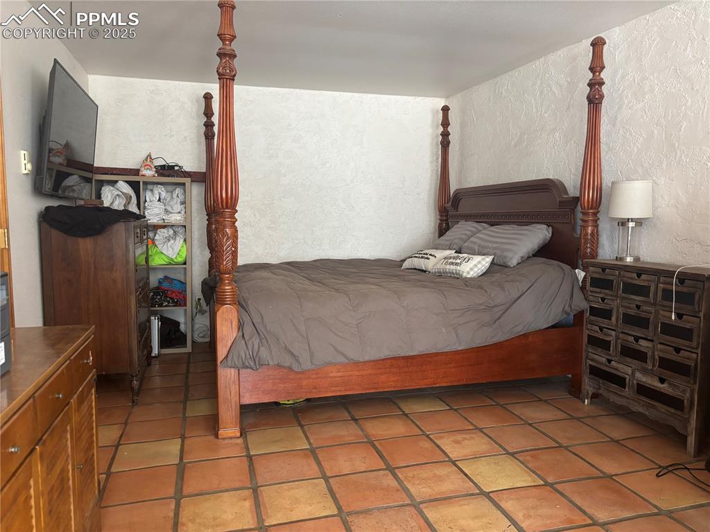 Image 15 of 25: Bedroom featuring a textured wall and light tile patterned floors