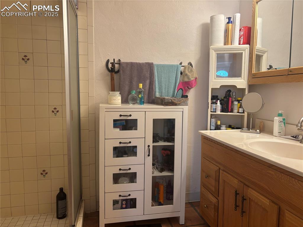 Image 17 of 25: Bathroom featuring a shower stall, vanity, and a textured wall