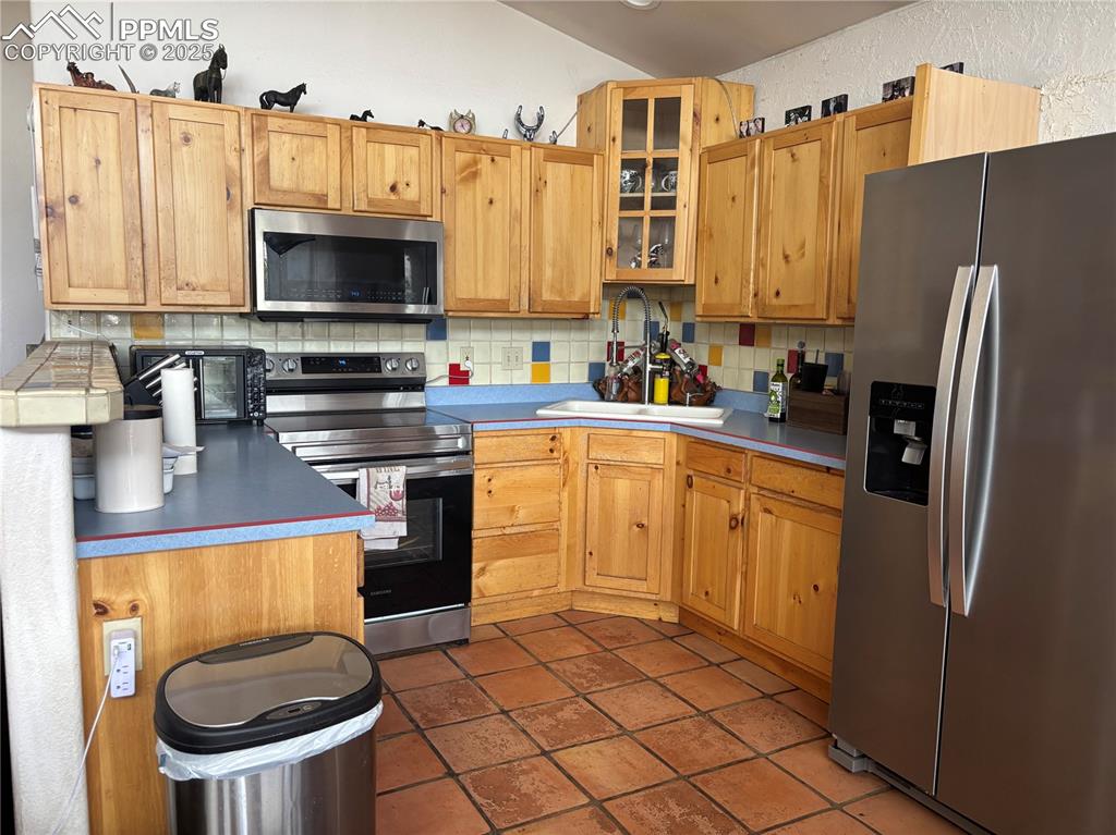 Image 7 of 25: Kitchen with appliances with stainless steel finishes, tasteful backsplash,