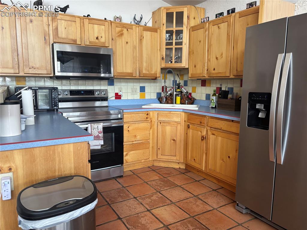 Image 8 of 25: Kitchen with stainless steel appliances, backsplash, glass insert cabinets,
