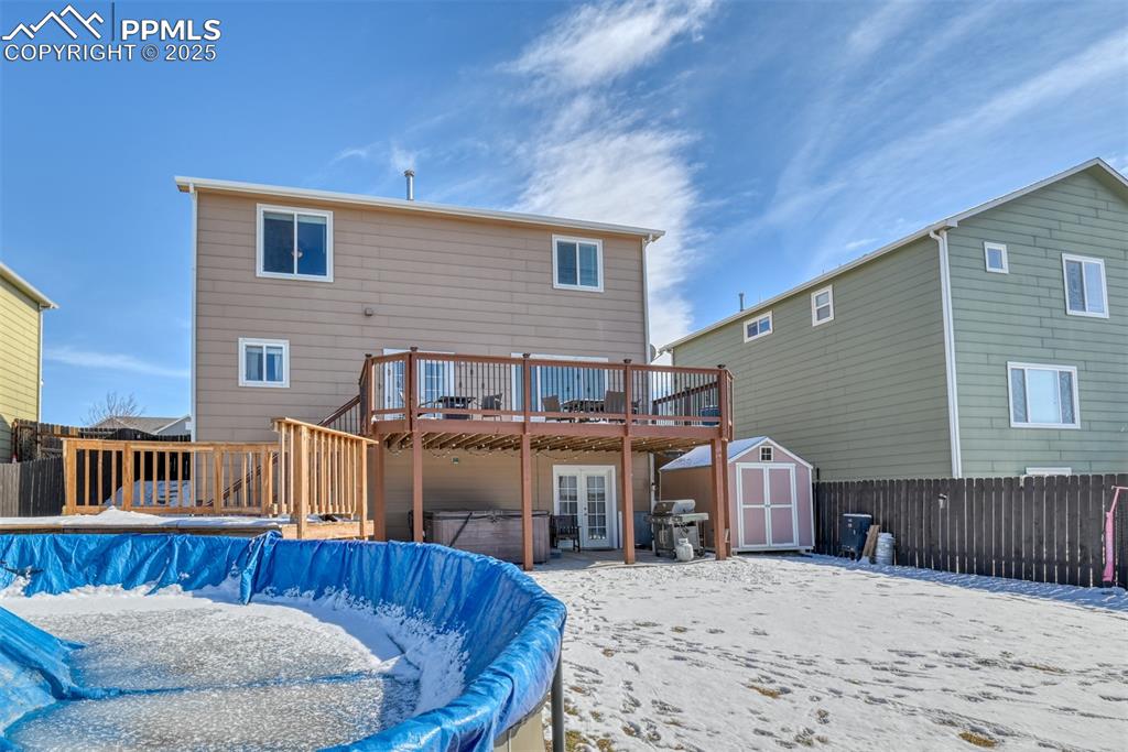 Image 40 of 42: Snow covered back of property with a pool with hot tub and a storage shed