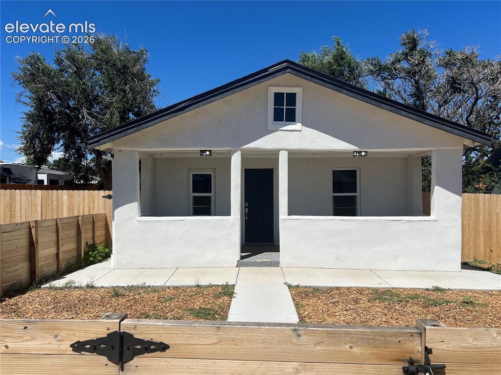 Caption: Main Hose - White stucco exterior with a covered porch, black asphalt shingle roof, and a wood priva