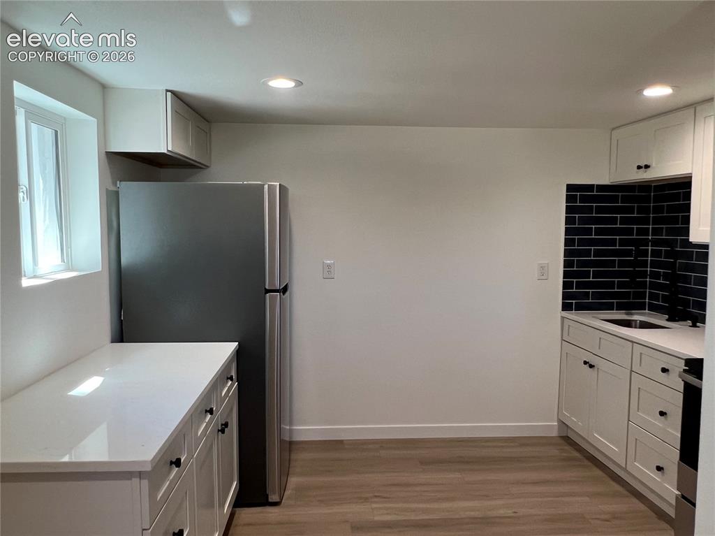 Image 16 of 23: Cottage - White shaker cabinetry, dark blue subway tile backsplash, stainle