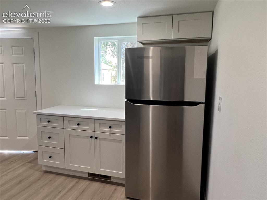 Image 17 of 23: Cottage - White shaker cabinetry, dark blue subway tile backsplash, stainle