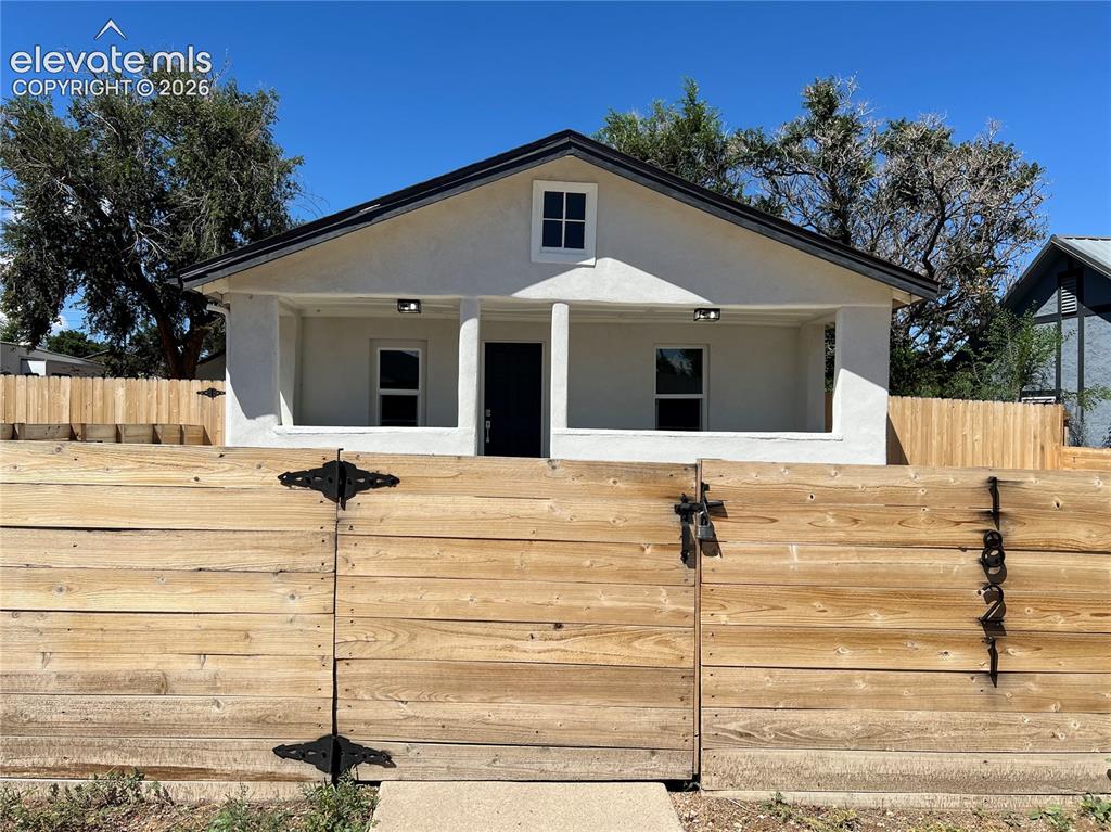 Image 2 of 23: White stucco exterior with a covered porch, dark entry door, and a prominen