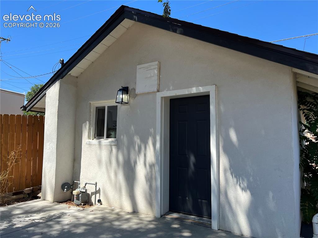Image 22 of 23: Cottage - Stucco exterior with black trim, a wood fence, and a black exteri