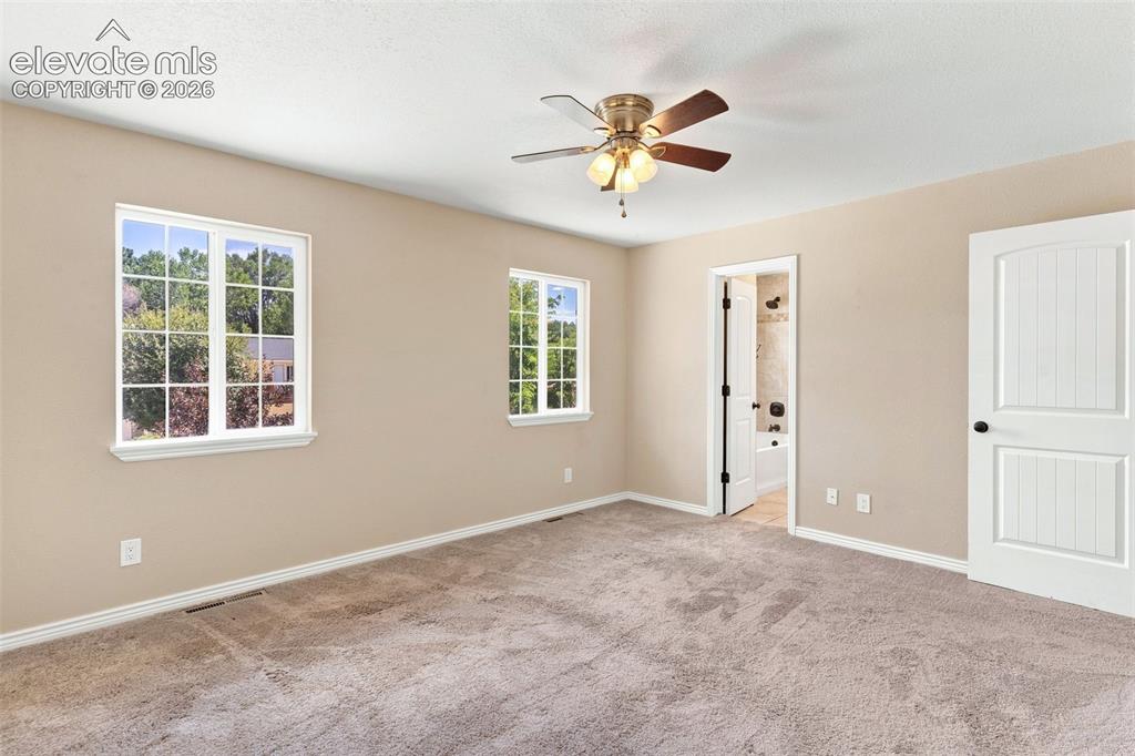 Image 20 of 39: Spacious primary bedroom with view into adjoining full bath.