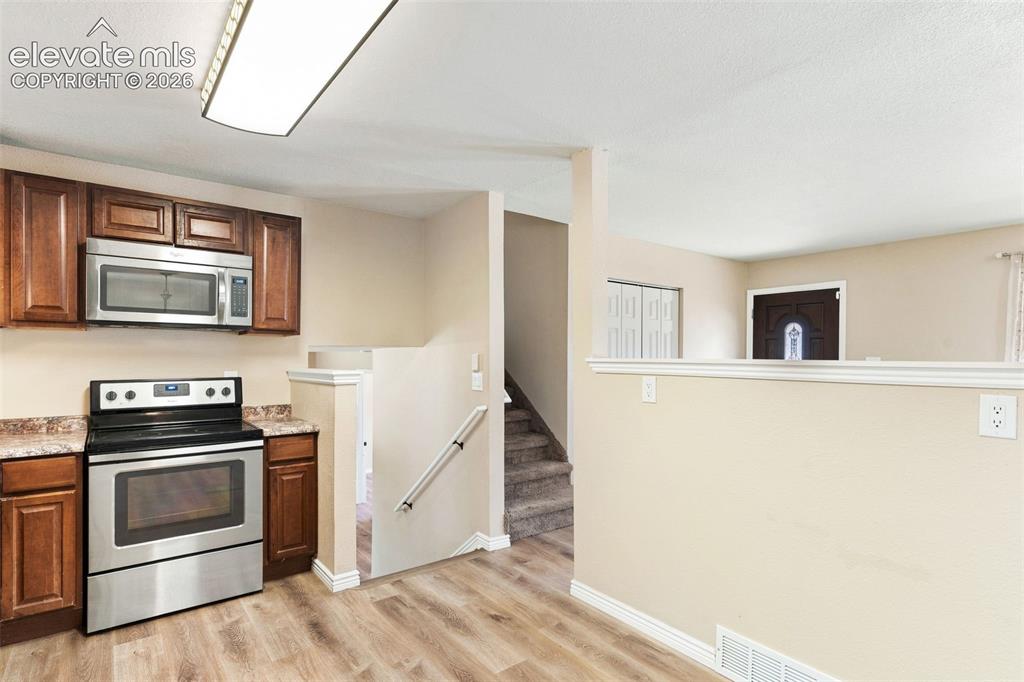 Image 7 of 39: Staircases to the upper and lower levels are adjacent to the kitchen.