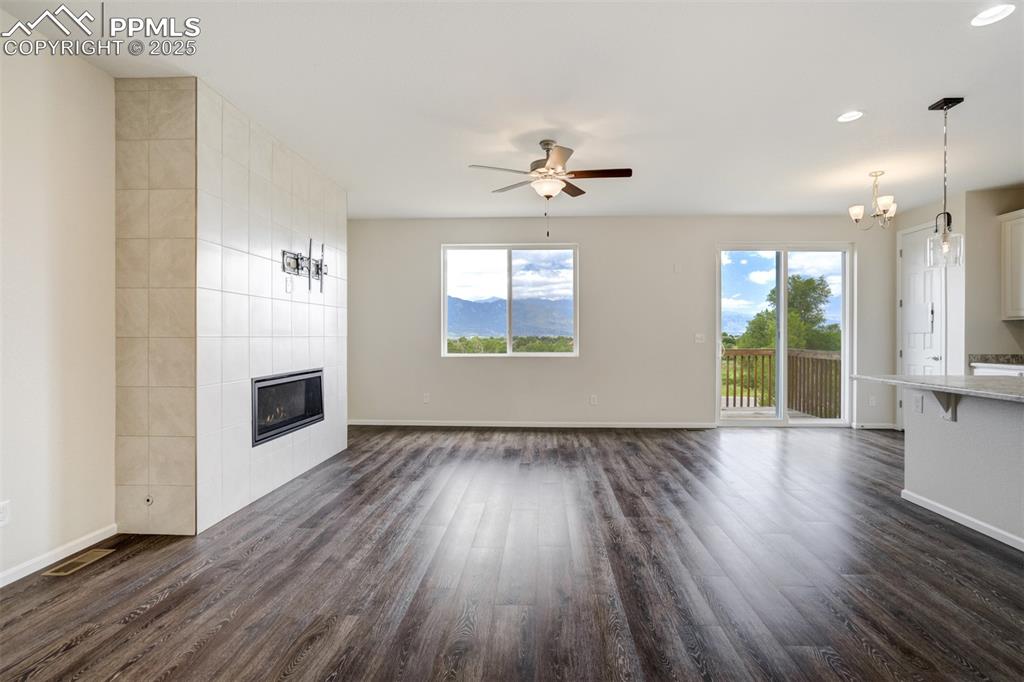 Image 10 of 44: Unfurnished living room featuring dark wood-style flooring, a tile fireplac