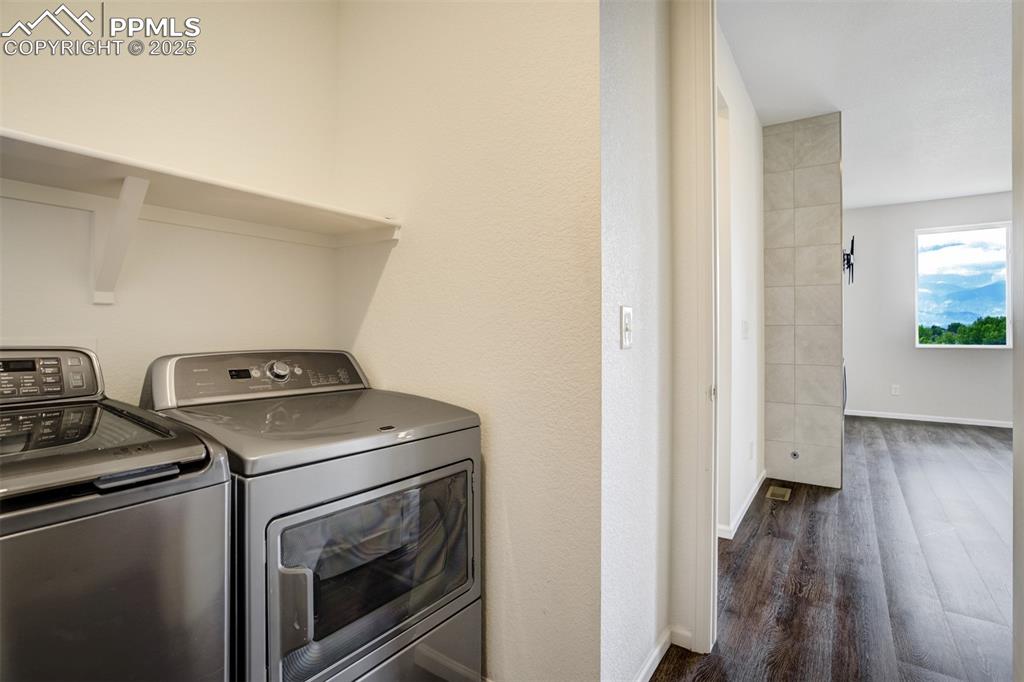 Image 22 of 44: Main level laundry room with separate washer and dryer and dark wood-type f
