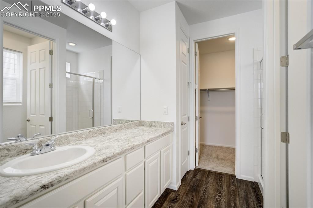 Image 23 of 44: Full bathroom with a shower stall, wood finished floors, vanity, and a walk