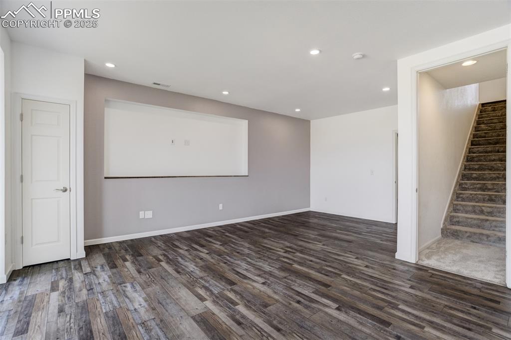 Image 26 of 44: Empty room featuring dark wood-style floors, stairway, and recessed lightin