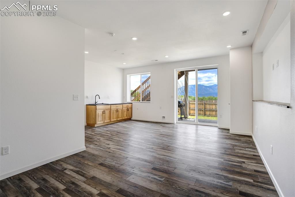 Image 28 of 44: Unfurnished living room featuring dark wood finished floors, recessed light
