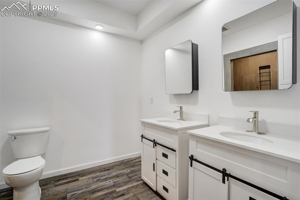 Image 34 of 44: Bathroom with wood finished floors and two vanities