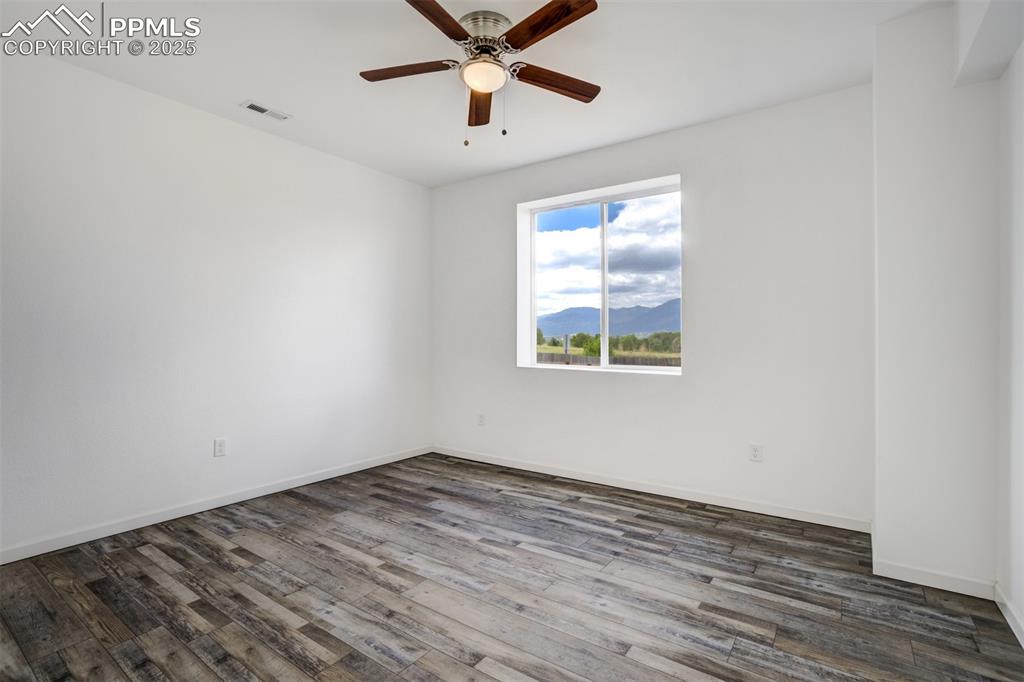 Image 39 of 44: Spare room featuring ceiling fan, dark wood finished floors, and a mountain