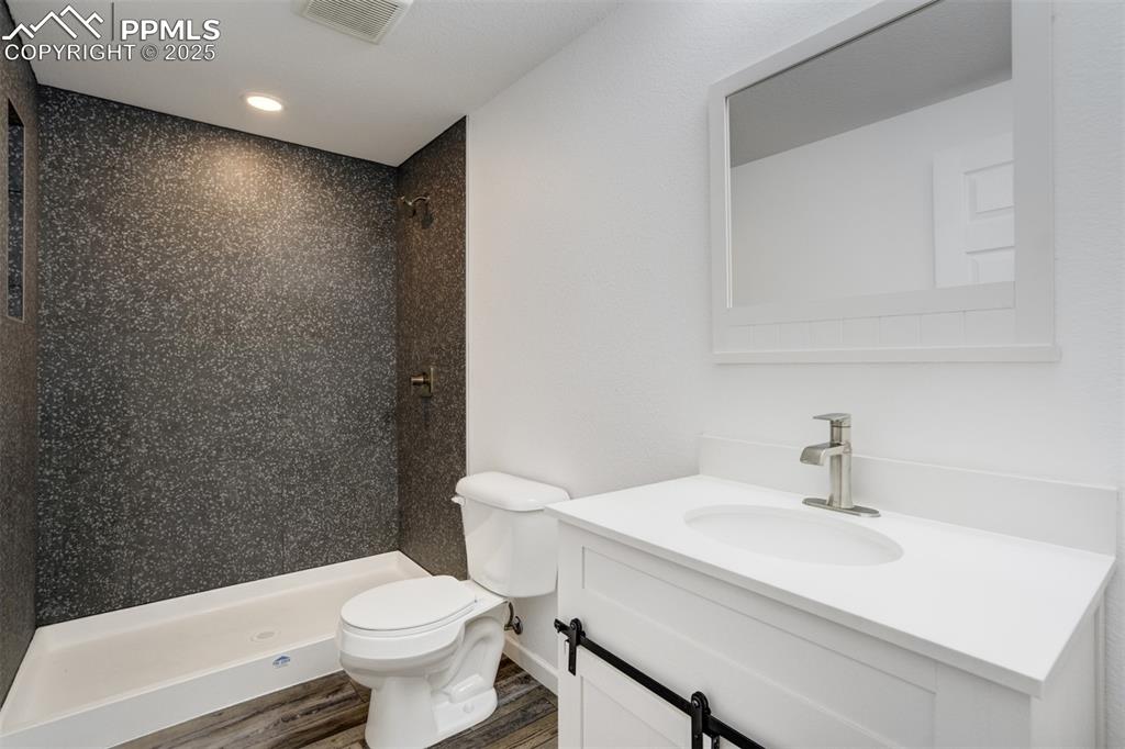 Image 41 of 44: Full bathroom featuring a shower stall, vanity, wood finished floors, and r