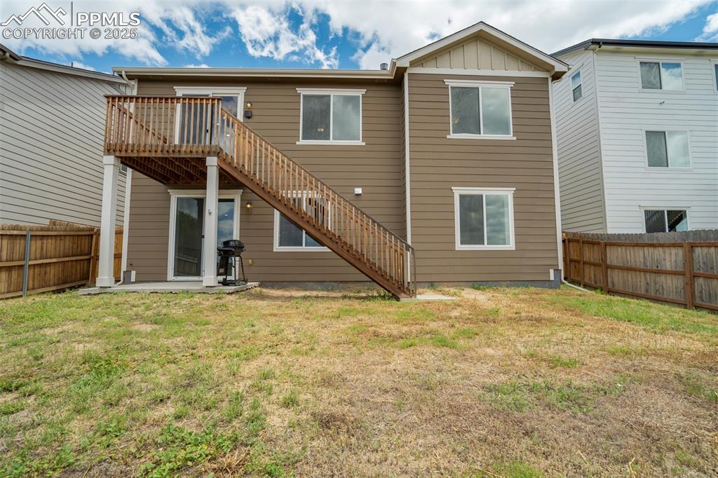 Image 44 of 44: Back of house featuring stairway, a deck, a fenced backyard, and board and