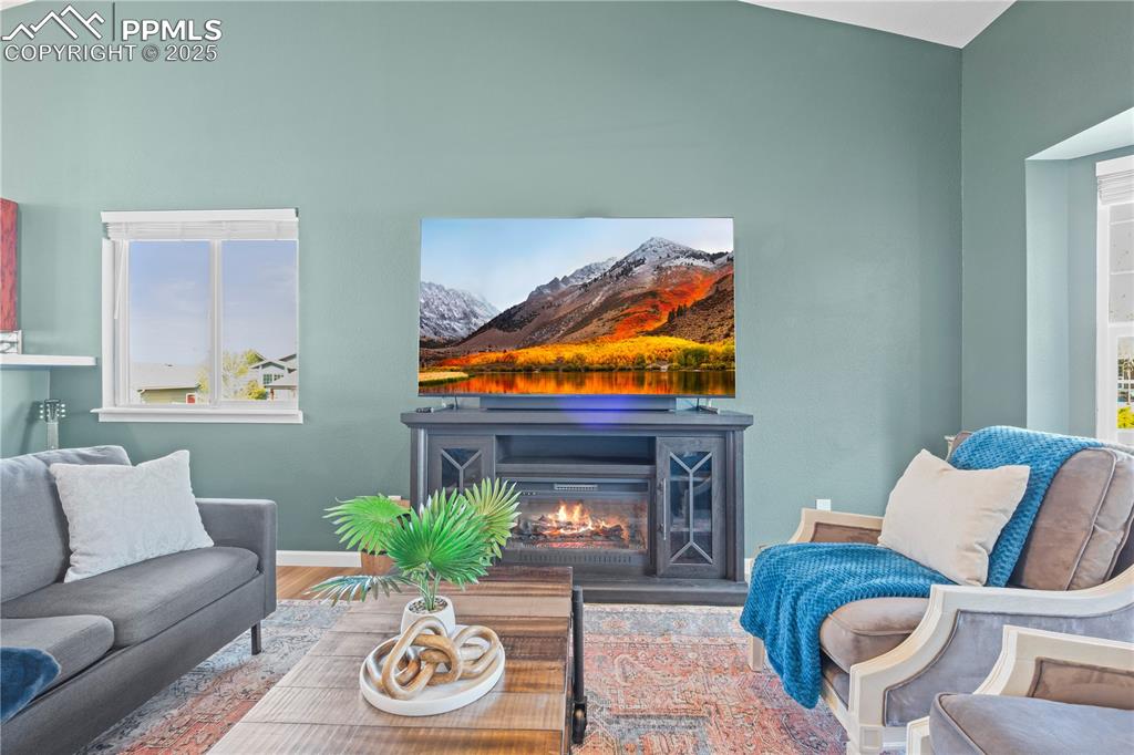 Image 4 of 40: Living area featuring a glass covered fireplace, and wood finished floors