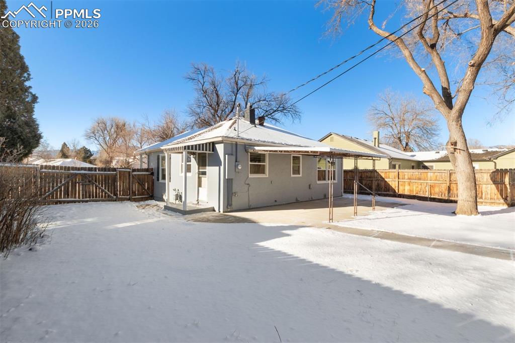 Image 25 of 31: Large yard with mature trees and new concrete patio with covered awning.