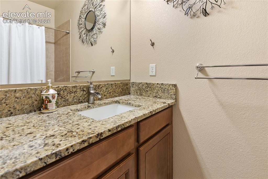 Image 10 of 29: Bathroom vanity with a granite countertop, undermount sink, and wood-finish