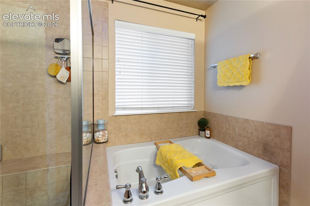 Image 16 of 29: Built-in tub with chrome fixtures, tiled surround, and privacy window