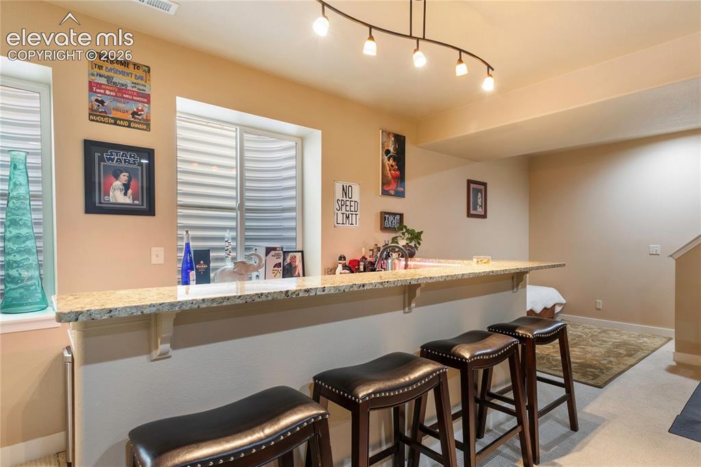 Image 18 of 29: Built-in bar with a light-toned granite-style countertop, a stainless steel