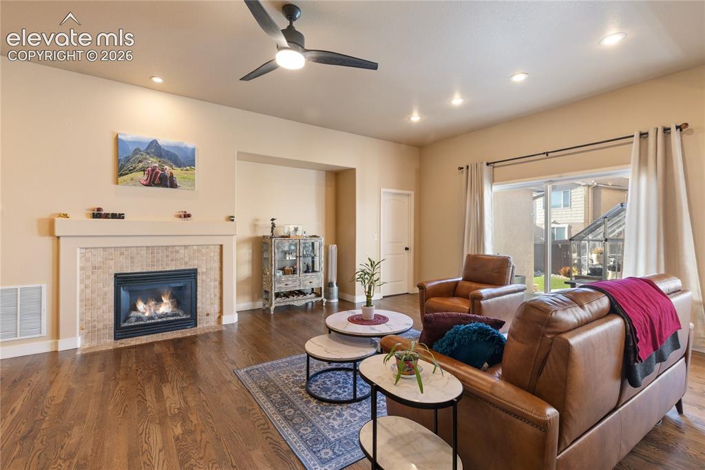Image 22 of 29: Warm wood-finish flooring with recessed lighting and a ceiling fan