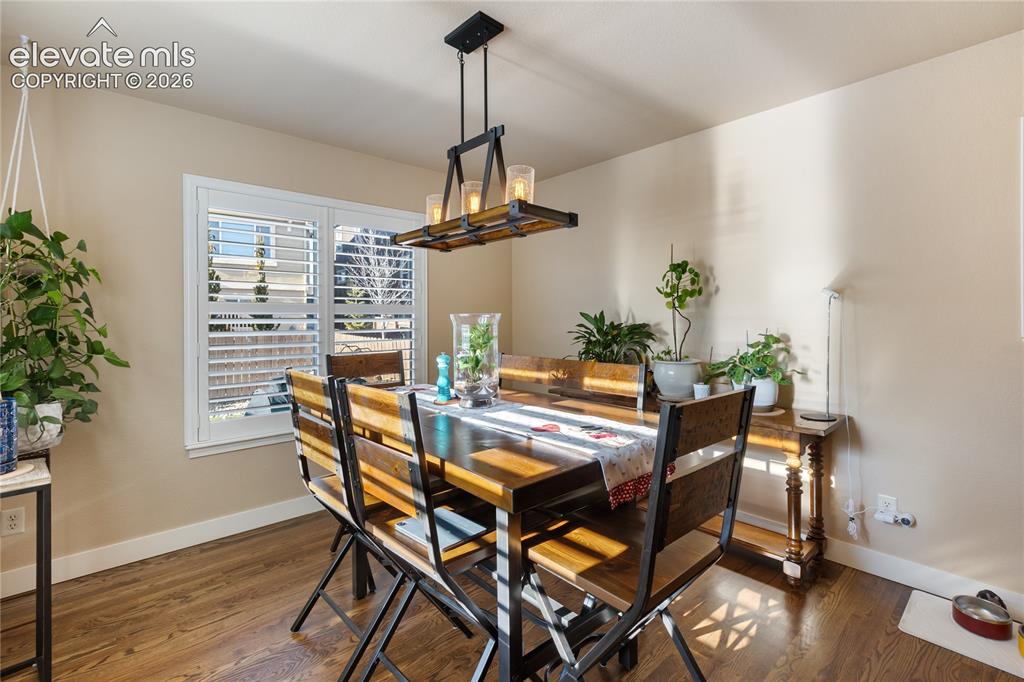 Image 7 of 29: Dining area featuring wood-finish flooring, white window shutters, and a co