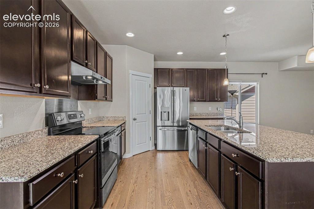 Image 10 of 39: Kitchen featuring dark wood cabinetry, light granite-style countertops, and