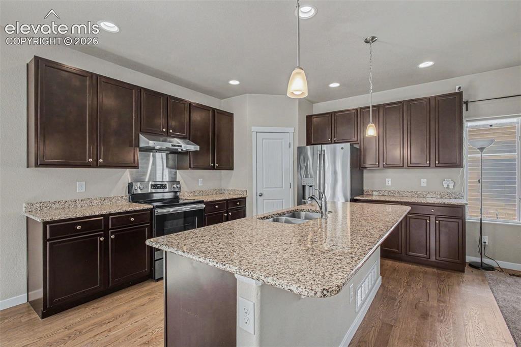Image 11 of 39: Kitchen featuring an island with a double basin stainless steel sink, grani