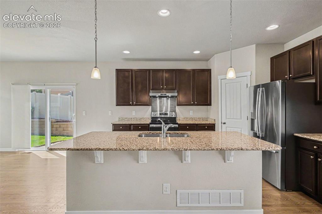 Image 13 of 39: Kitchen featuring an expansive island with a double basin sink, stone count