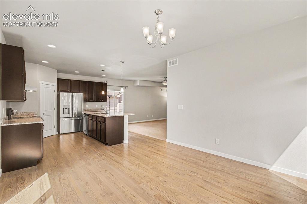 Image 15 of 39: Spacious kitchen and dining area featuring wood-finish flooring, dark wood